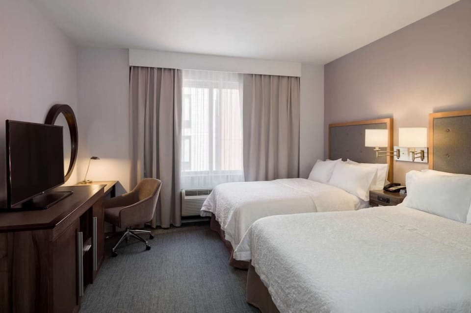 Room with two double beds, work desk, and soft lighting