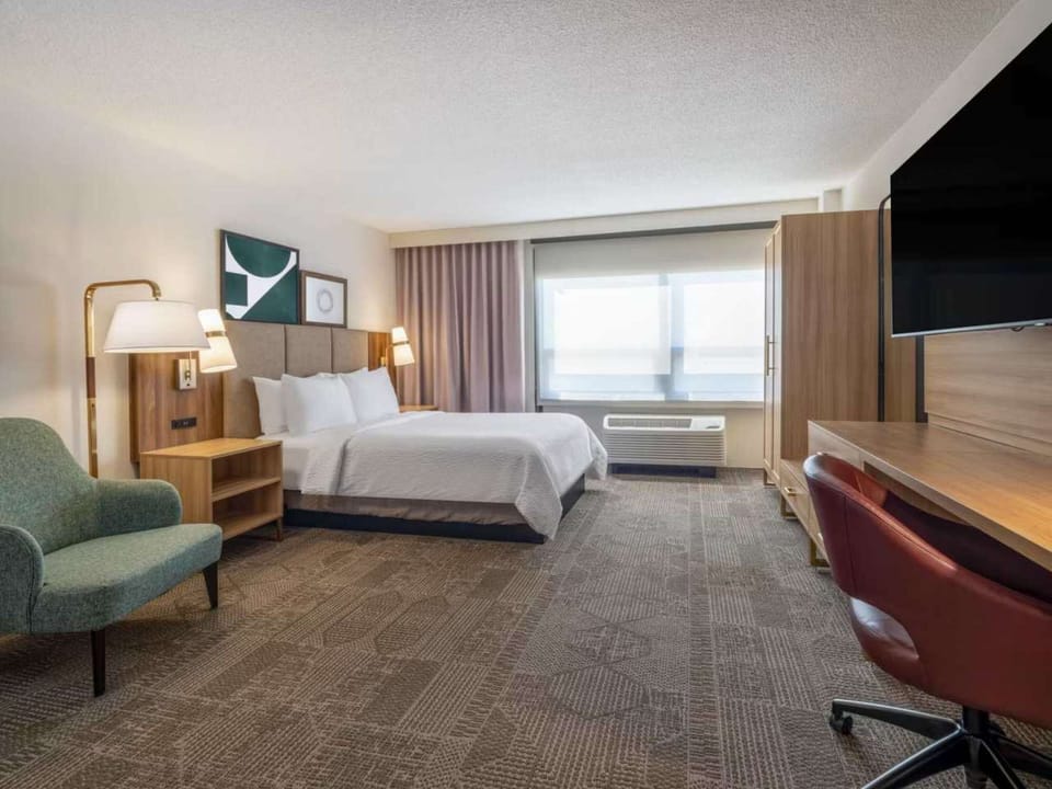 Bright guest room with queen bed, work desk, and window light