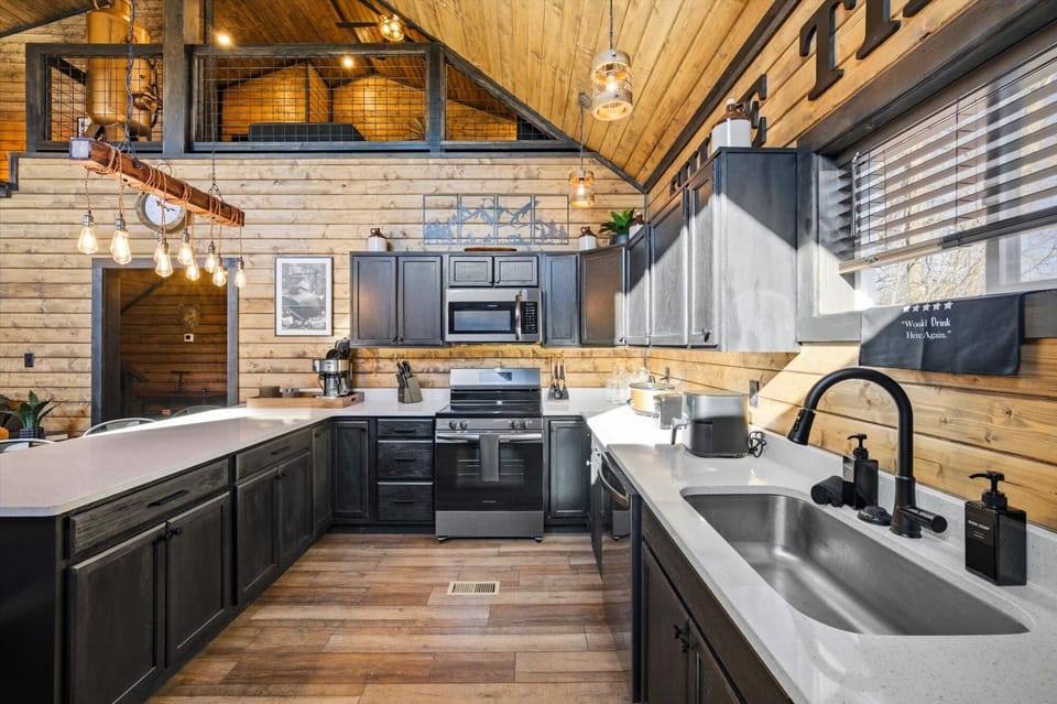 Chef's kitchen with dark cabinetry and stainless steel appliances.