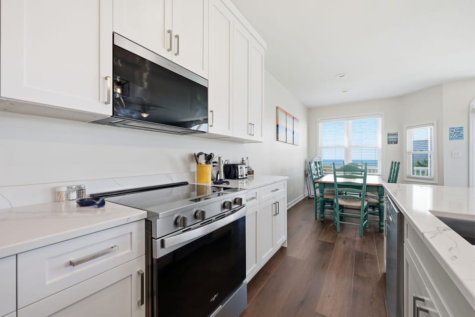 The fully equipped kitchen and dining area feature modern appliances, bright coastal light, and stunning water views—making every meal a memorable experience.
