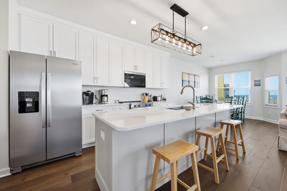 Picture yourself cooking in this modern kitchen with sleek appliances, spacious countertops, and an inviting island for morning coffee. Ocean views await just beyond the dining area.