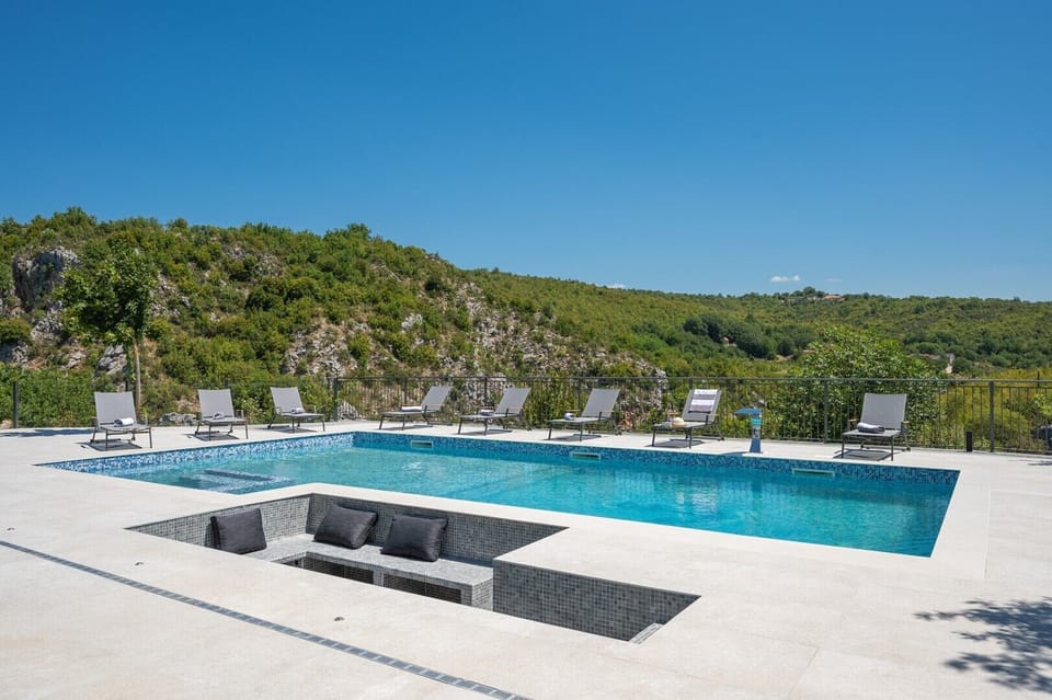 Large heated pool featuring a unique sunken seating area and mosaic tiles.