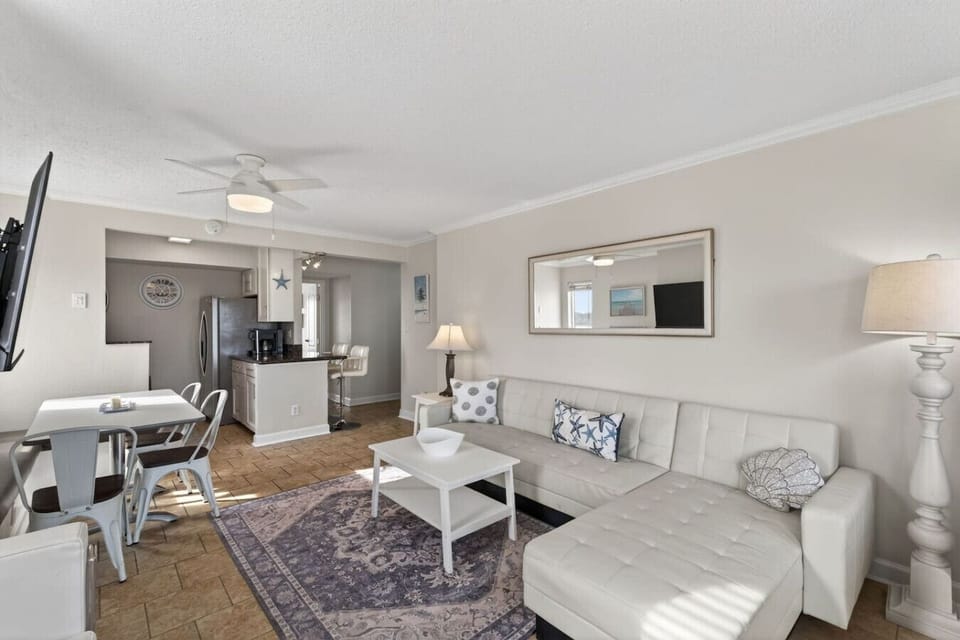 Bright, coastal-inspired living space with plush seating, stylish décor, and an open layout that flows seamlessly into the dining area and kitchen.