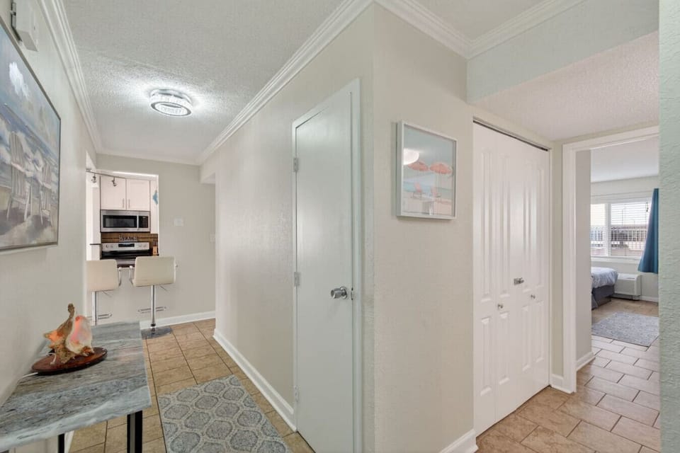 Bright hallway with coastal artwork and ample storage, leading to the kitchen and bedrooms.