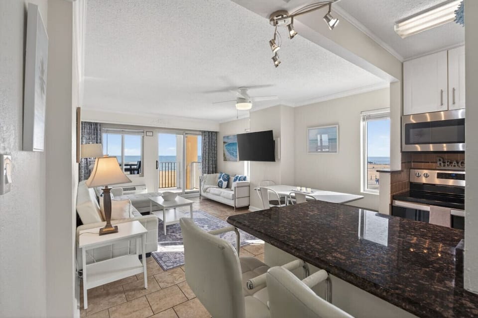 Spacious, open-concept kitchen and living area with granite countertops, modern appliances, and comfortable seating, all framed by natural light and ocean views.