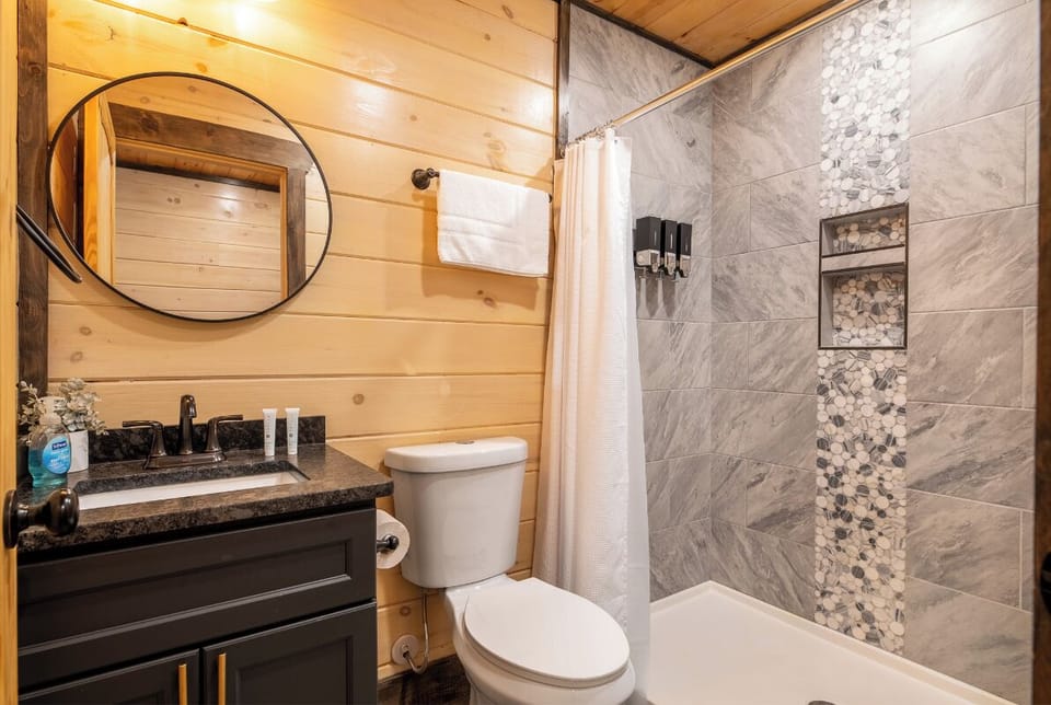 Refresh in your stylish bathroom featuring a luxurious marble-tiled shower and warm wood accents that create the perfect cabin retreat.