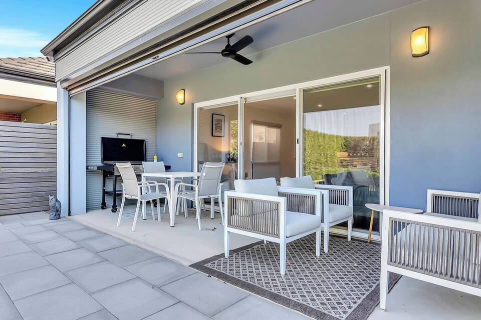 The covered patio is designed for easy outdoor living, with a gas BBQ, dining table and outdoor lounge, plus a ceiling fan for comfort on warm days.