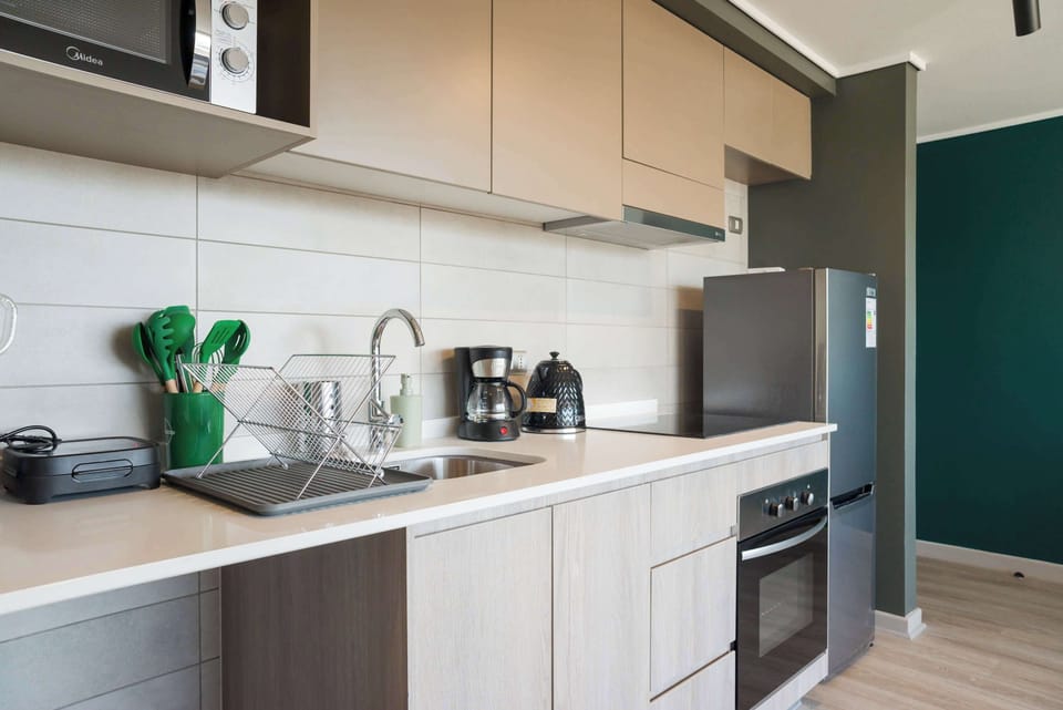 Sleek and modern kitchen with all essentials for a comfortable stay, featuring stainless steel appliances and stylish accents.