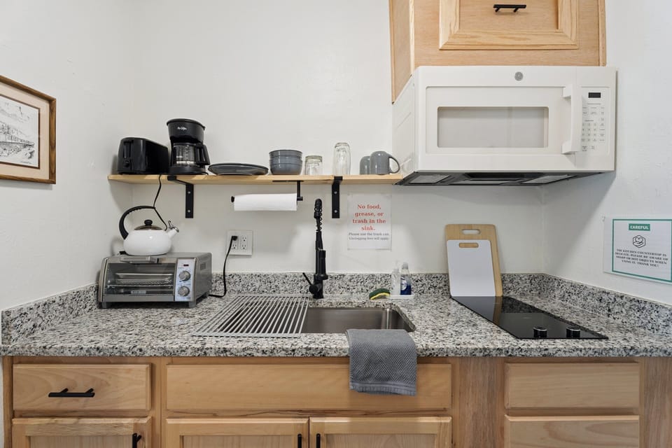 From coffee to quick bites, this tidy kitchen setup has you covered with modern finishes and open shelving for easy access.