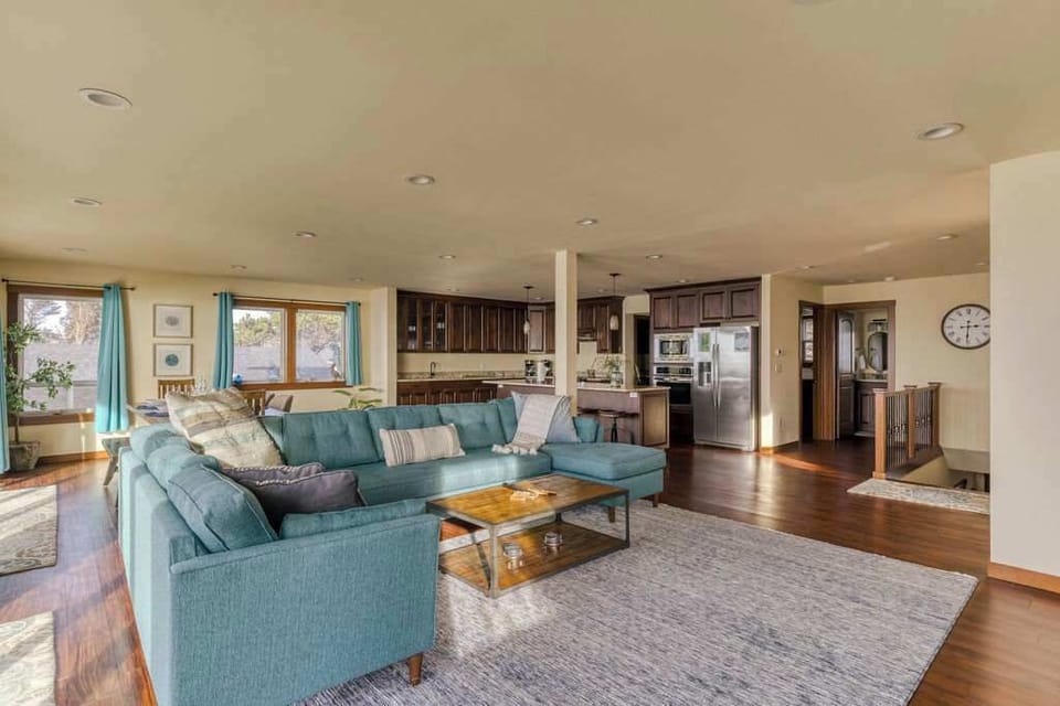 From the sofa you can see clear through the kitchen and dining area to the ocean beyond — true open-plan coastal living.
