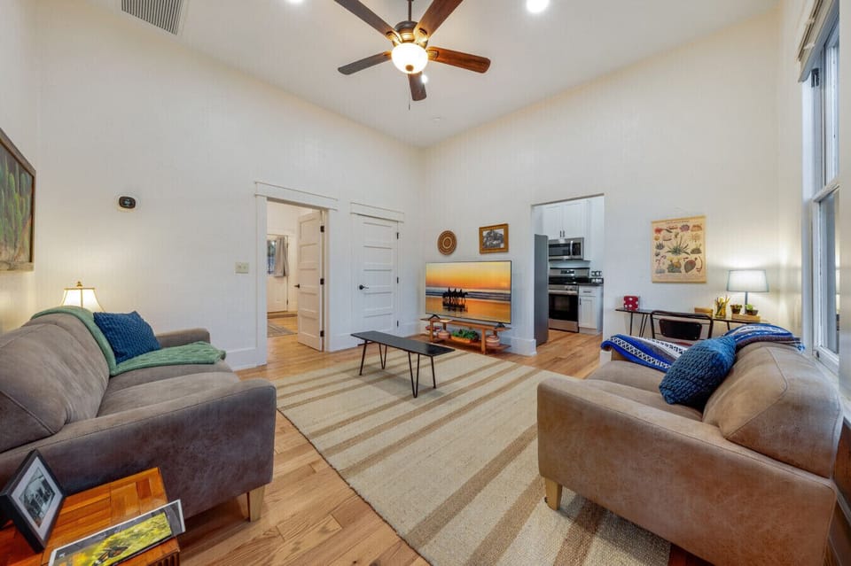 Cozy living room with plenty of comfortable seating, desk and chair, ceiling fan, and smart TV