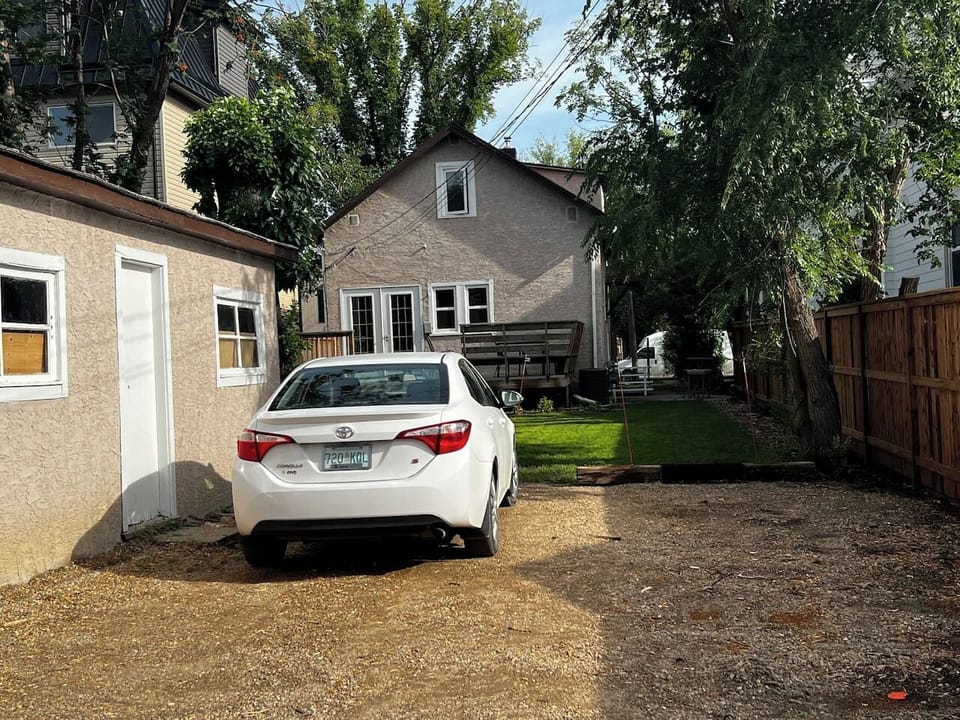 View of the back yard greenspace with elm trees and a place to park your vehicle. 