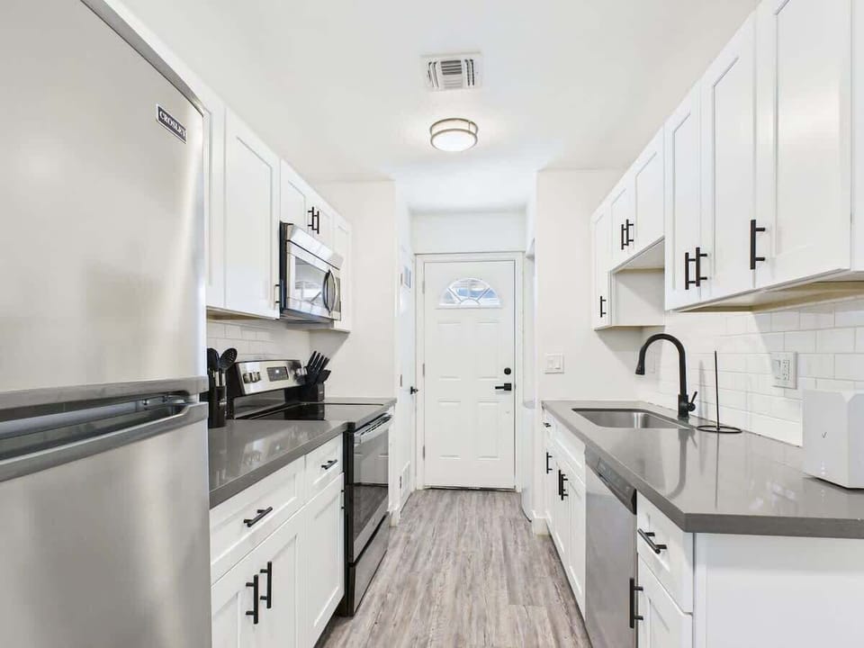 Unit 2: Fully equipped kitchen stocked with basic cooking essentials, stainless steel appliances, access to the shared backyard, and a washer and dryer.