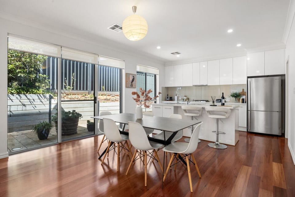 Gather around the dining area for shared meals, with sunlight streaming in and sliding doors opening to the courtyard for a breezy indoor–outdoor feel.