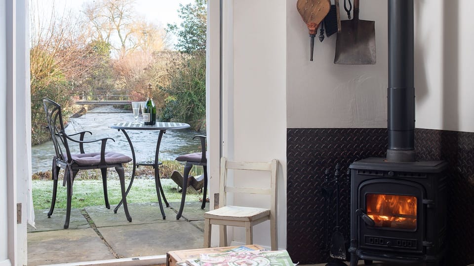 A two-seater bistro table is positioned just outside the front door, providing a charming space for sitting outdoors.