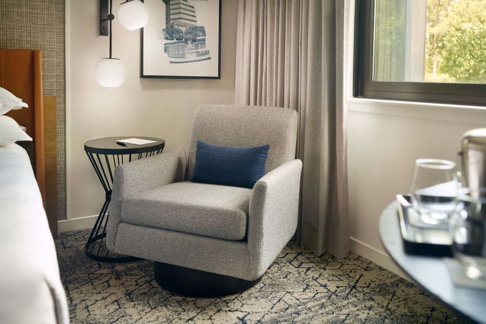 Soft armchair with blue pillow next to round table and window