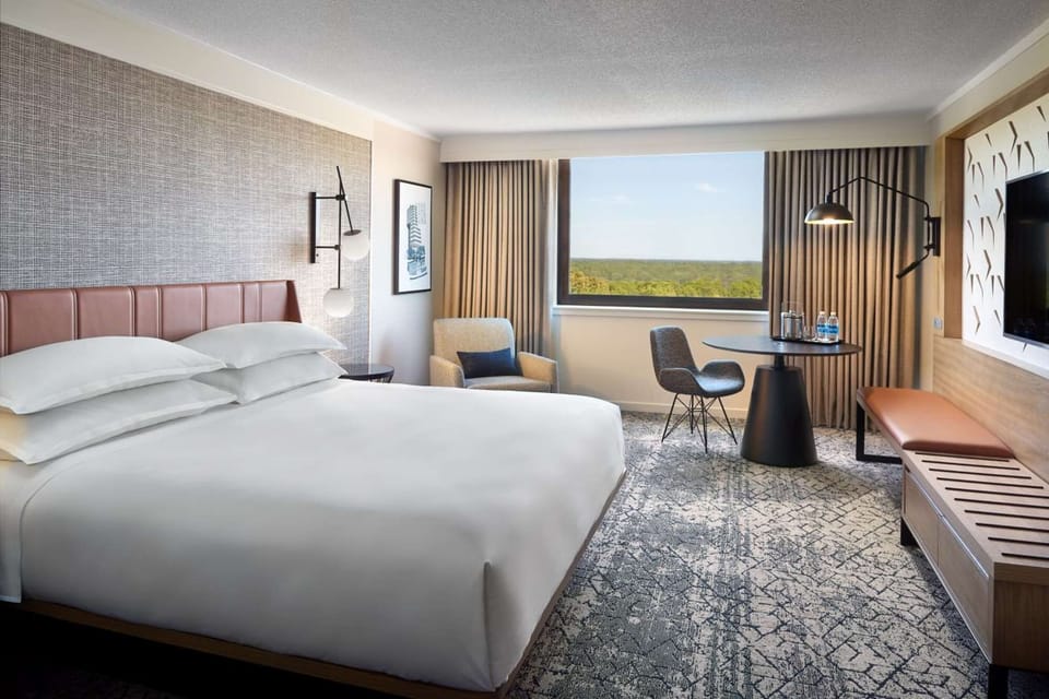 King room with wide window, seating, and desk by the view