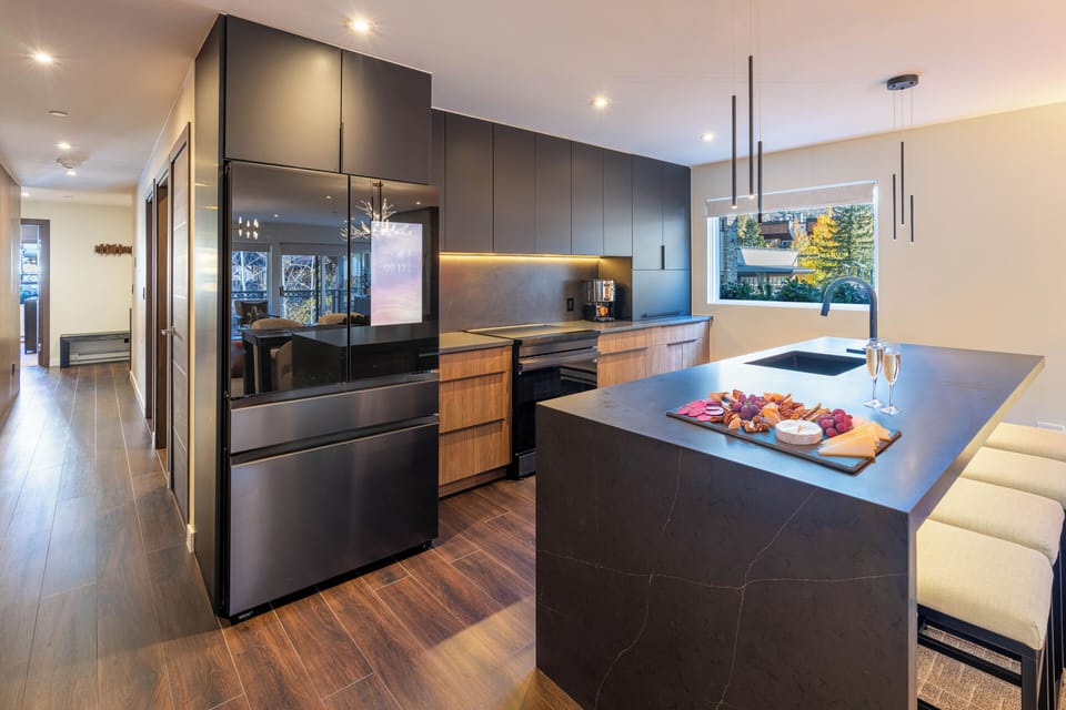 You'll love preparing meals in this stunning modern kitchen featuring sleek dark cabinetry, premium appliances, and a spacious island perfect for entertaining.
