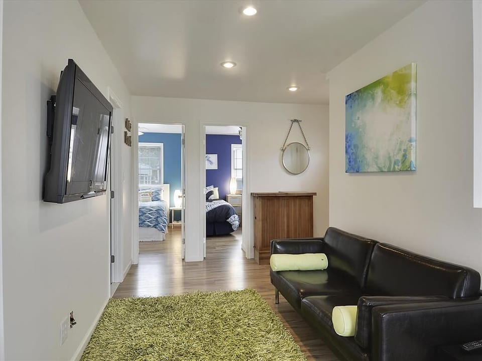 Open living space view with light wood floors, colorful accents, and an area rug.
