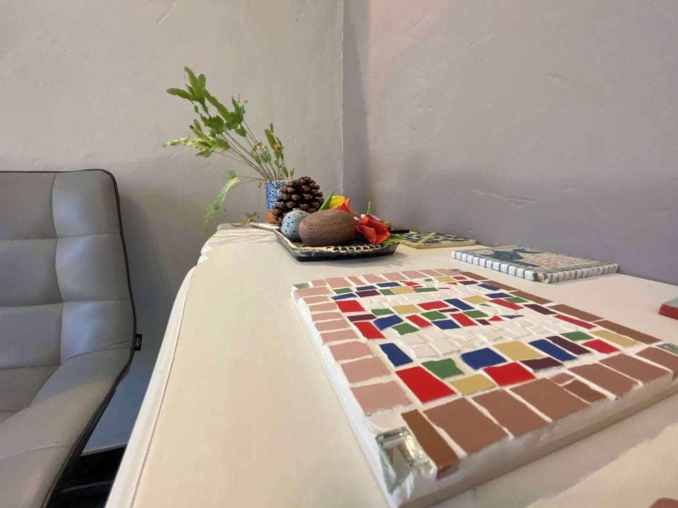 Table à manger blanche avec sets colorés, canapé et vase décoratif