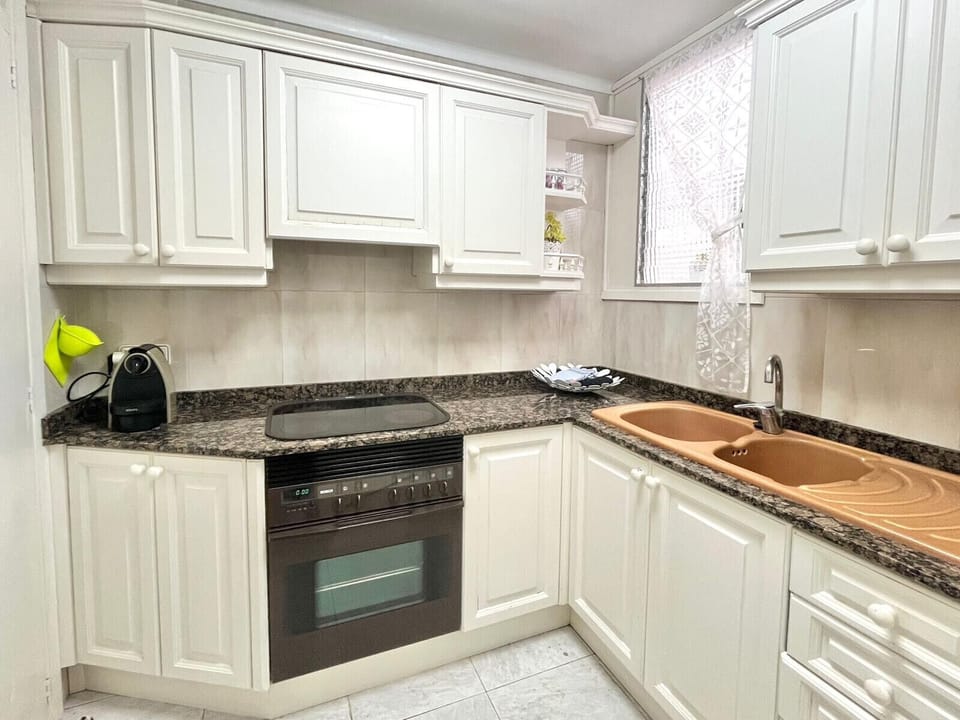Fully equipped kitchen in Apartment Gola with white cabinets, granite worktop, oven, ceramic hob and double sink, bright and practical.