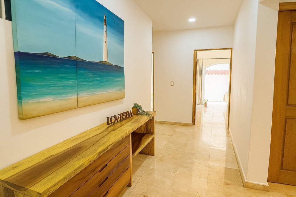 Entrada interior decorada con arte caribeño y muebles de madera
