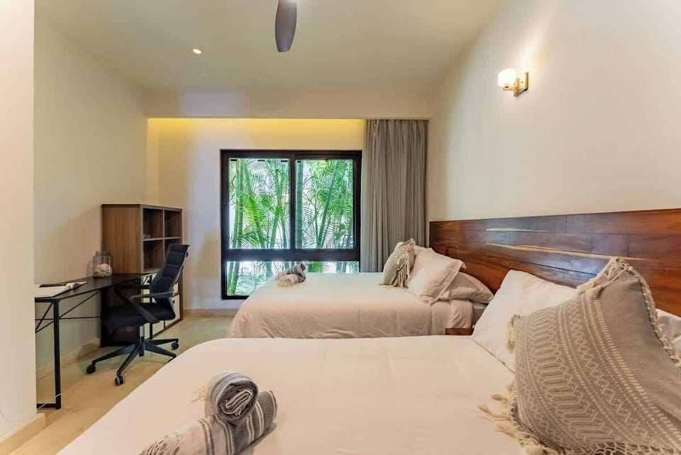 "Perfecta para trabajar o descansar: habitación con escritorio, dos camas y vista a la vegetación."