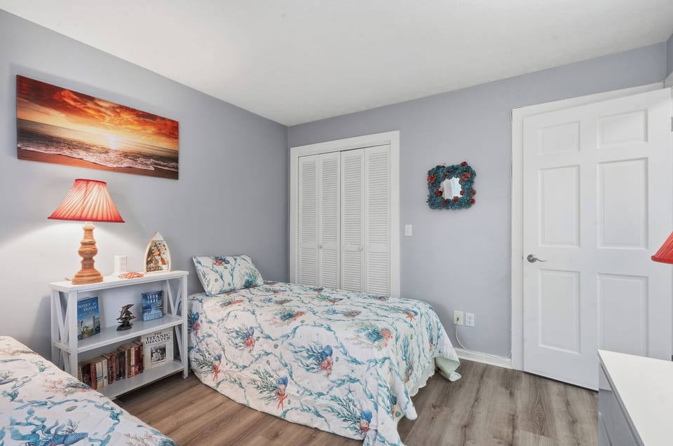 Drift off in your cozy twin bedroom featuring ocean-themed bedding, warm lighting, and charming coastal artwork to inspire peaceful dreams.