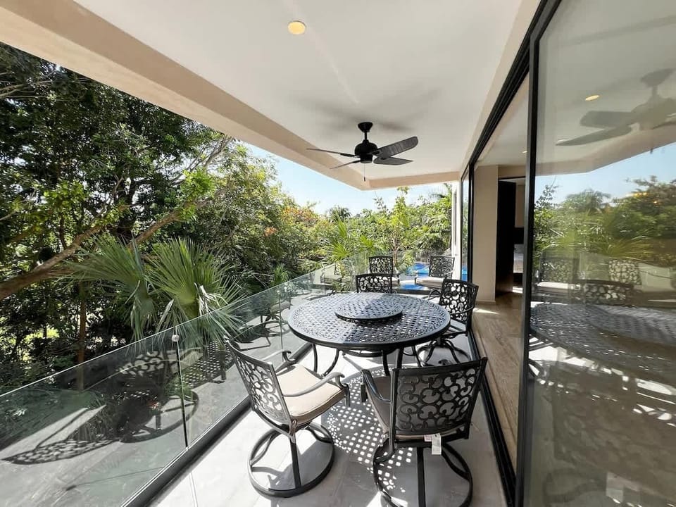 Terraza rodeada de naturaleza tropical 
Espaciosa terraza con comedor exterior y ventilador de techo. Un rincón perfecto para desayunos al aire libre o cenas al atardecer con vistas al campo de golf y las copas de los árboles.