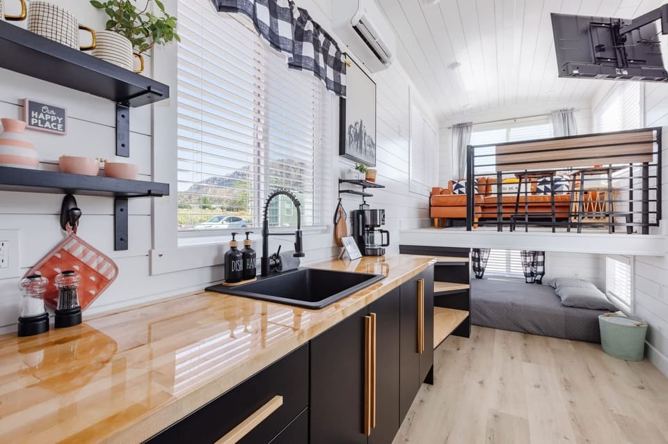 Open-concept tiny home layout featuring a fully equipped kitchen, cozy main-floor bed, and elevated loft living area. Bright windows, modern finishes, and smart space design create a comfortable Southern Utah retreat near Zion.