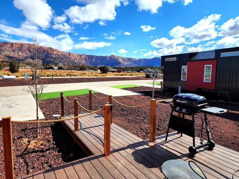 Charming tiny home with a cozy private deck, BBQ grill, and fire pit for outdoor dining and relaxing. Enjoy mountain views, convenient parking right in front, and peaceful desert nights perfect for stargazing.