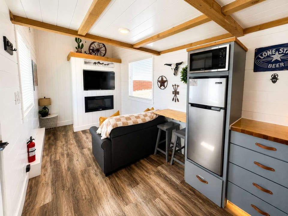 Bright, open kitchen with warm wood countertops, full-size fridge, microwave, and sink. Efficient layout flows into the cozy living area, creating a functional space for cooking, relaxing, and enjoying your stay.