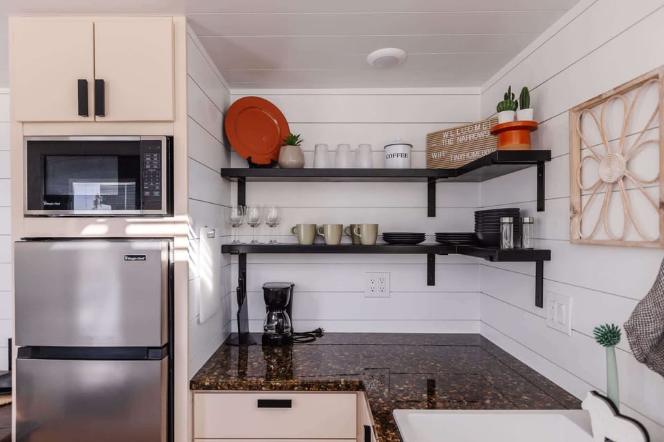 Well-stocked kitchen with fridge, freezer, microwave, coffee maker, dishes, glassware, and counter space for simple meals during your getaway.