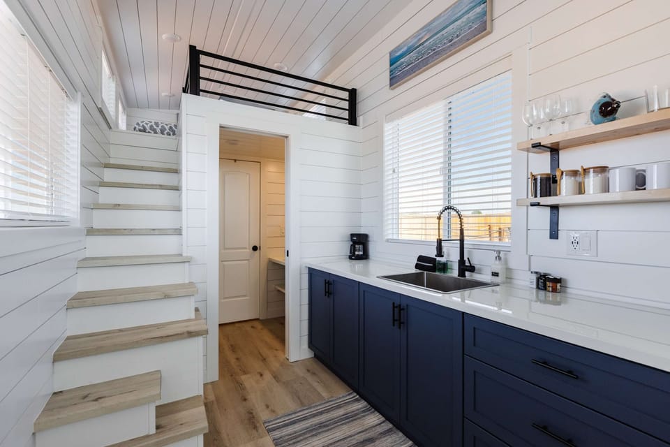 Enjoy a functional kitchen featuring modern cabinetry, stainless steel appliances, quartz countertops, and large windows that fill the space with natural light.