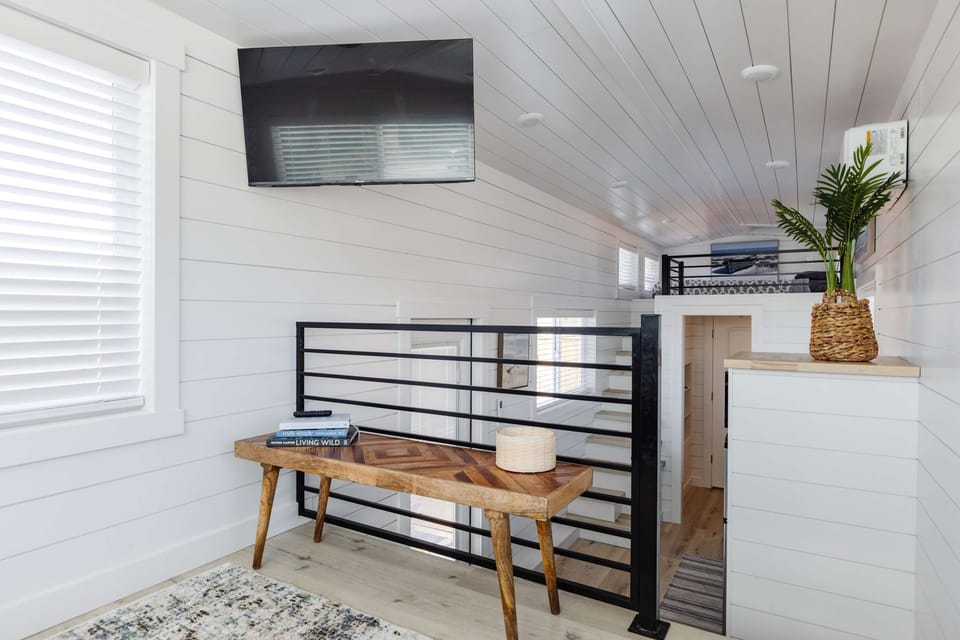The thoughtfully designed loft lounge provides additional space to relax while overlooking the open-concept interior of this modern tiny home.