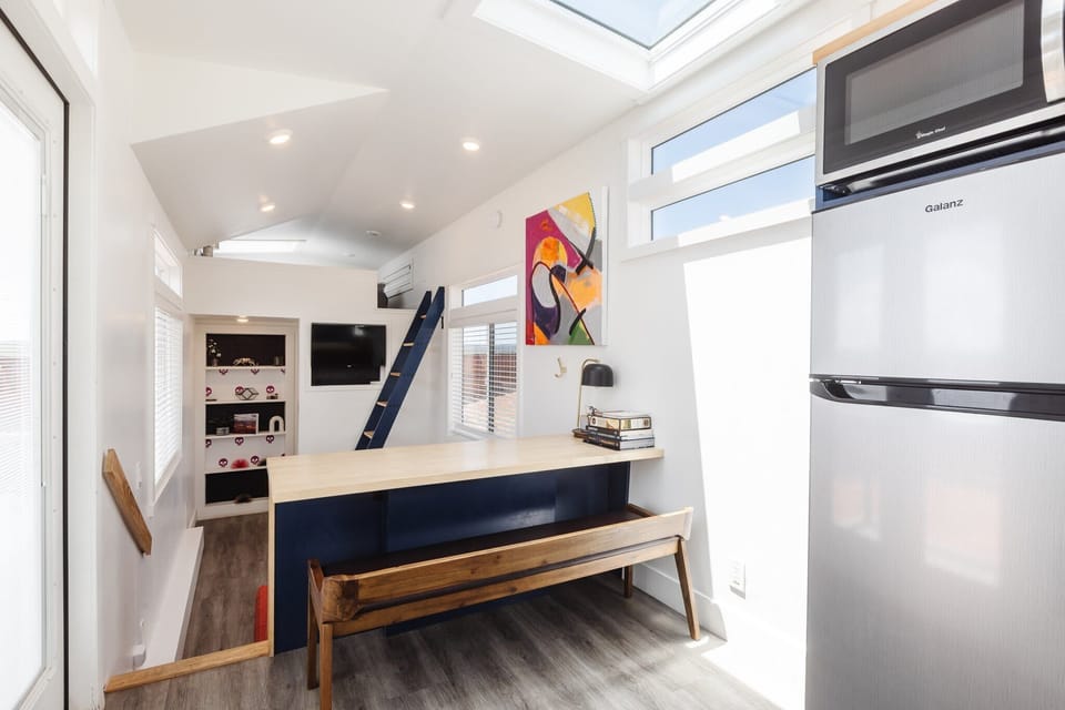 Bright dining area with bench seating, loft access, and natural light from oversized windows and skylights. This multifunctional space is perfect for enjoying meals, planning adventures, or relaxing in your modern Southern Utah tiny home.