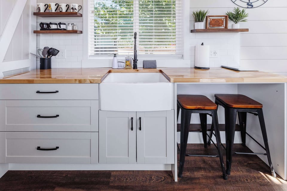 Modern kitchen with generous counter space, open shelving, cooking essentials, and seating for two.