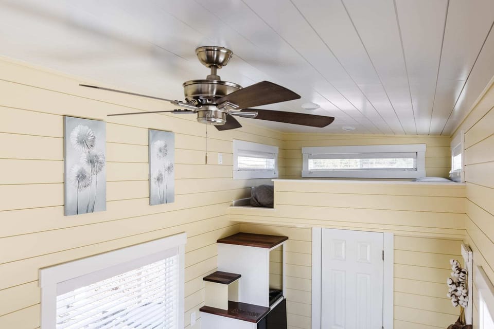 Bright loft bedroom with a queen-size bed, ceiling fan, windows, and an open layout overlooking the living area below. This inviting sleeping space offers comfort and charm for your Southern Utah getaway.