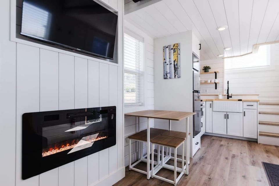 The dining area features a stylish table with comfortable barstools for seating. Perfect for meals, work, or gatherings with friends, this space offers a cozy and functional setup that maximizes comfort while maintaining a sleek, space-saving design.