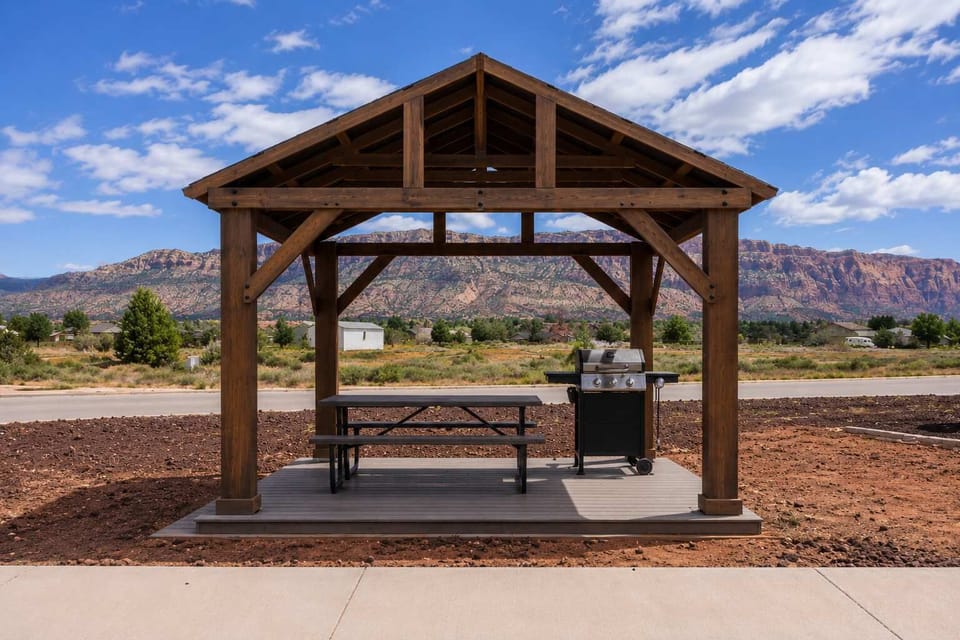 Covered outdoor pavilion with picnic bench seating, located next to the community playground. A nearby shaded area offers a comfortable place to relax, enjoy meals, and take a break from the sun while spending time outdoors.