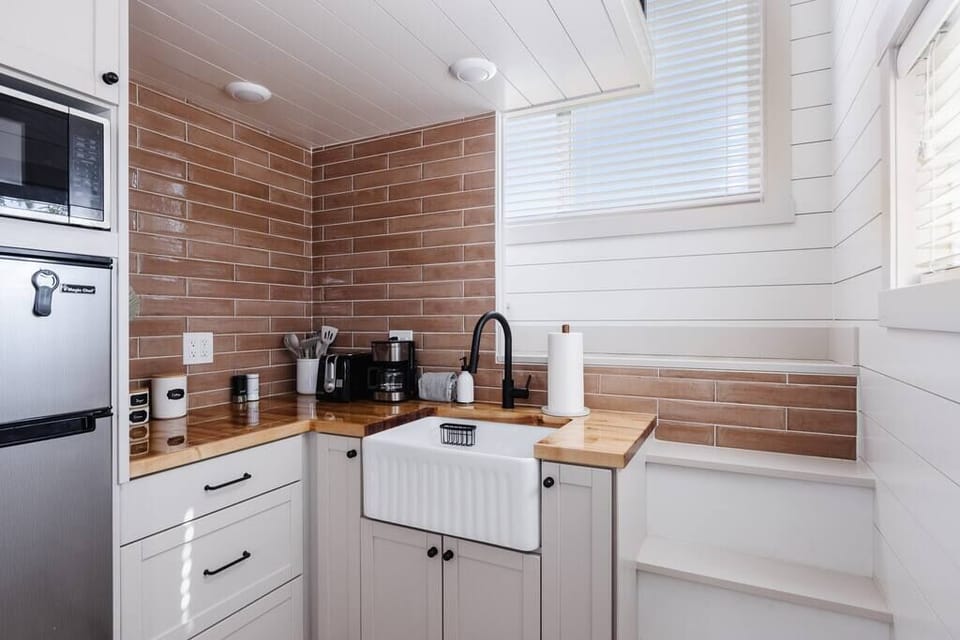 The kitchen is fully equipped with a refrigerator, freezer, microwave, cooktop, and sink with hot/cold water. Enjoy coffee from the coffee maker, with cookware, dishes, and utensils.