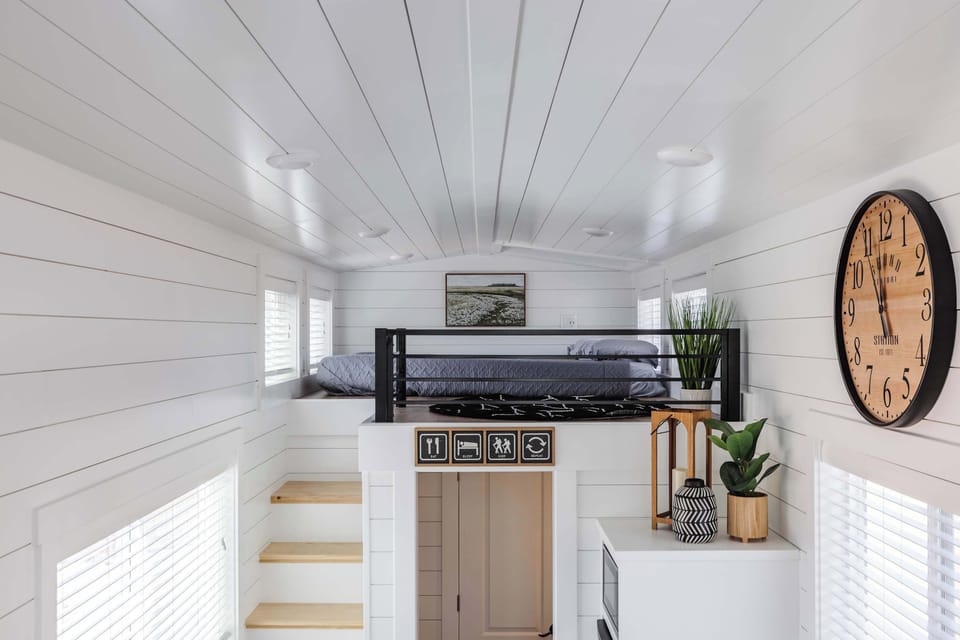 Follow the illuminated staircase to the cozy loft featuring a comfortable queen bed beneath a skylight, creating the perfect place to unwind after exploring Southern Utah.