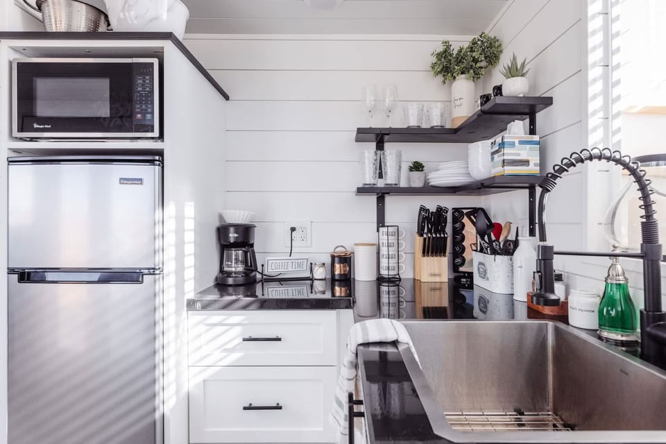 The kitchen is fully equipped with a refrigerator, freezer, microwave, cooktop, and sink with hot/cold water. Enjoy coffee from the coffee maker and ample counter space. Essentials include cookware, dishes, utensils, and plenty of storage cabinets.