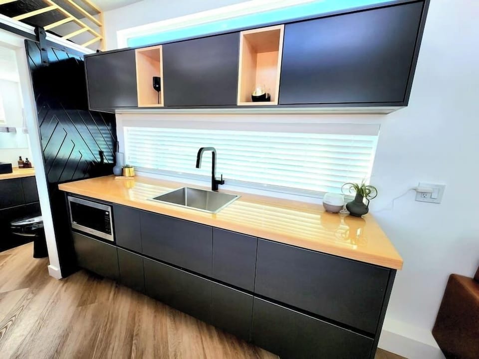 The kitchen is fully equipped with a refrigerator, freezer, microwave, cook-top, and sink with hot/cold water. Enjoy coffee from the coffee maker and ample counter space. Essentials include cookware, dishes, and utensils.