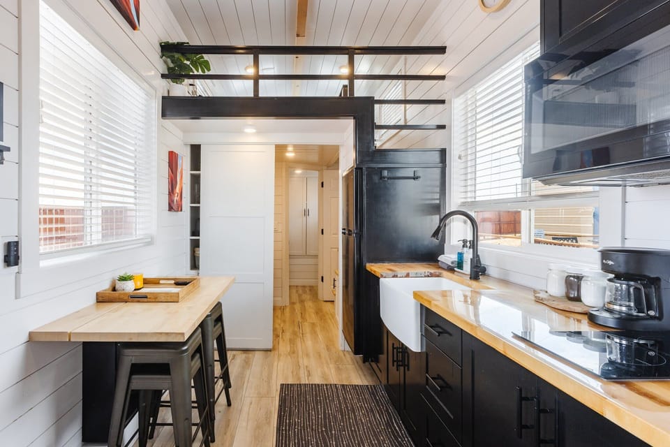 The cozy dining area features a stylish tabletop with comfortable barstools for seating. Perfect for meals or casual gatherings, this space is inviting and functional, offering a great spot to enjoy a meal or sip a drink with friends or family.