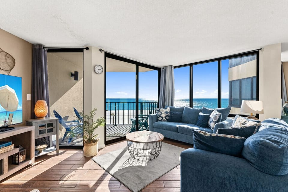 Gulf-front living room with panoramic ocean views, private balcony access, and a queen-size sleeper sofa for extra guests.