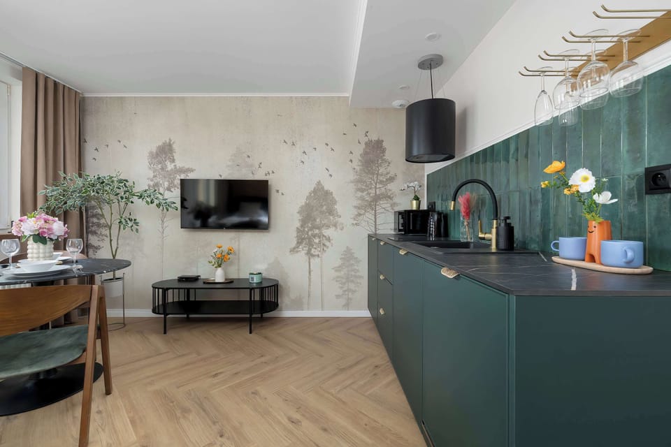 Stylish kitchenette with deep green cabinetry, patterned backsplash, and modern appliances.