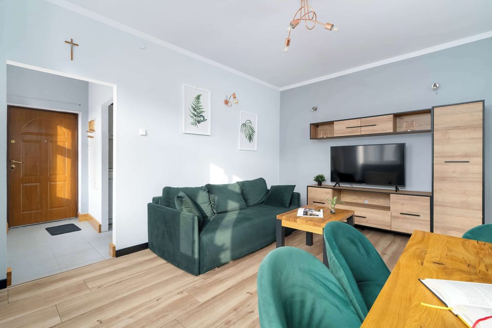 Bright living room with green sofa, wooden coffee table, and wall shelving.