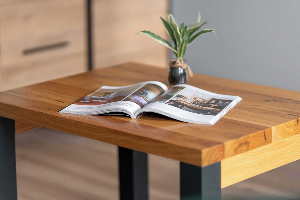 Close-up of wooden table with magazine and plant.