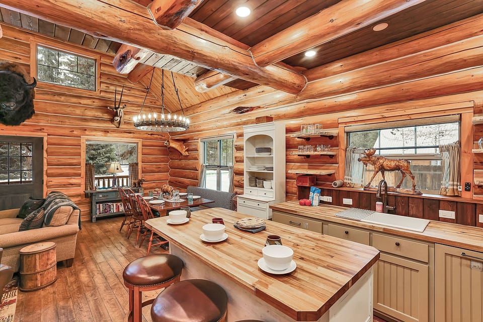 Enamel mugs, wood grain, and a well‑used cutting board give the kitchen its nostalgic, cabin‑camp feel